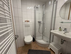 A modern bathroom with a glass-enclosed shower, a toilet, a sink, and a small step stool. - Vacation home "MeerZeit" - Holiday home over 3 floors, 65 m² living space with terrace (Dahme)