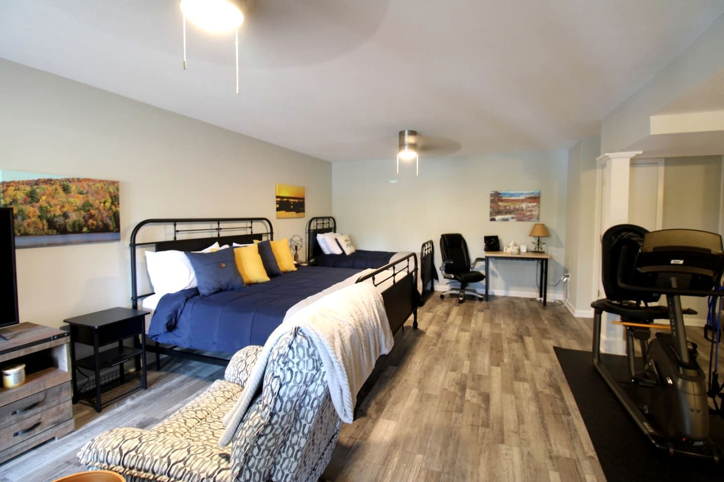 A bedroom with a bed, desk, chair, and a TV.