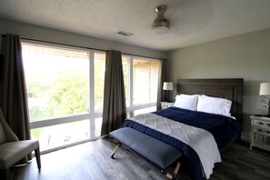 A bedroom with a bed, a chair, a nightstand, and a window with curtains. - Glorious Cabin with Fantastic Lake Sights in Hot Springs, Arkansas (Hot Springs)