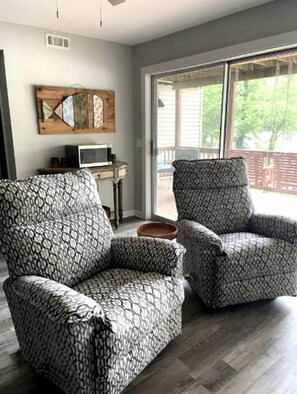A living room with two patterned armchairs, a wooden coffee table, a television, and a large window with a view of the outdoors. - Glorious Cabin with Fantastic Lake Sights in Hot Springs, Arkansas (Hot Springs)
