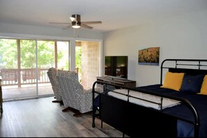 A bedroom with a bed, a TV, a chair, and a balcony with a view. - Glorious Cabin with Fantastic Lake Sights in Hot Springs, Arkansas (Hot Springs)
