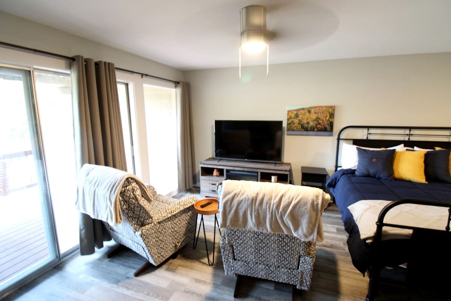 A hotel room with a bed, a sofa, a TV, and a small table.