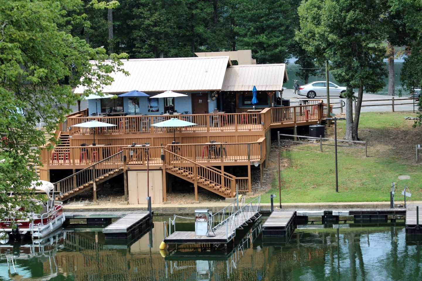 Een pand aan het water met een steiger, een houten terras met zitplaatsen buiten, en een gebouw met een wit dak.