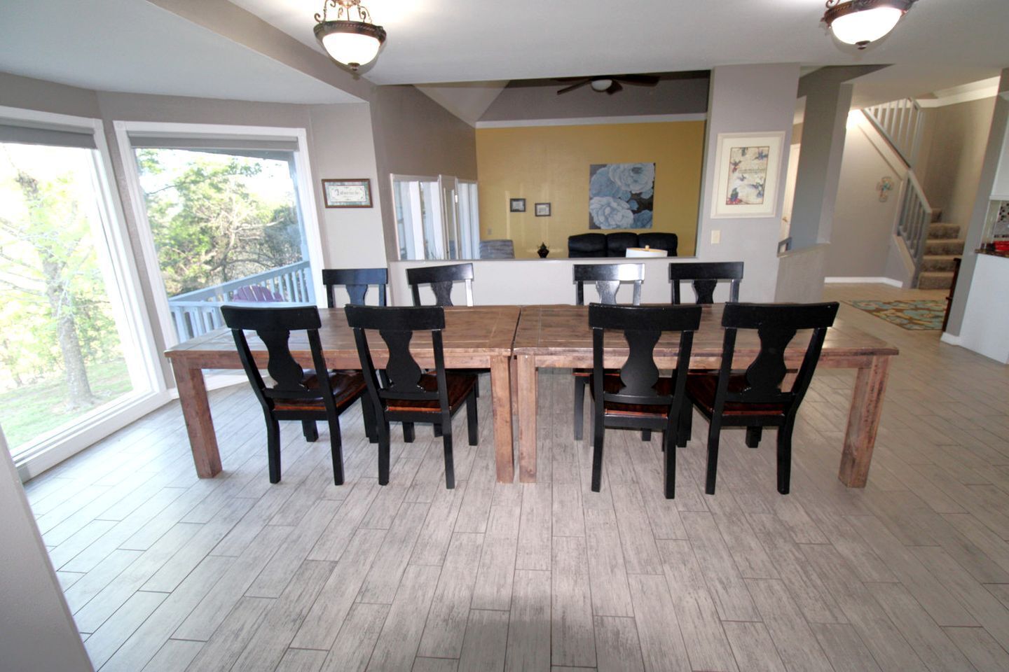 A dining area with a wooden table and chairs, a staircase, and a view of the outdoors.