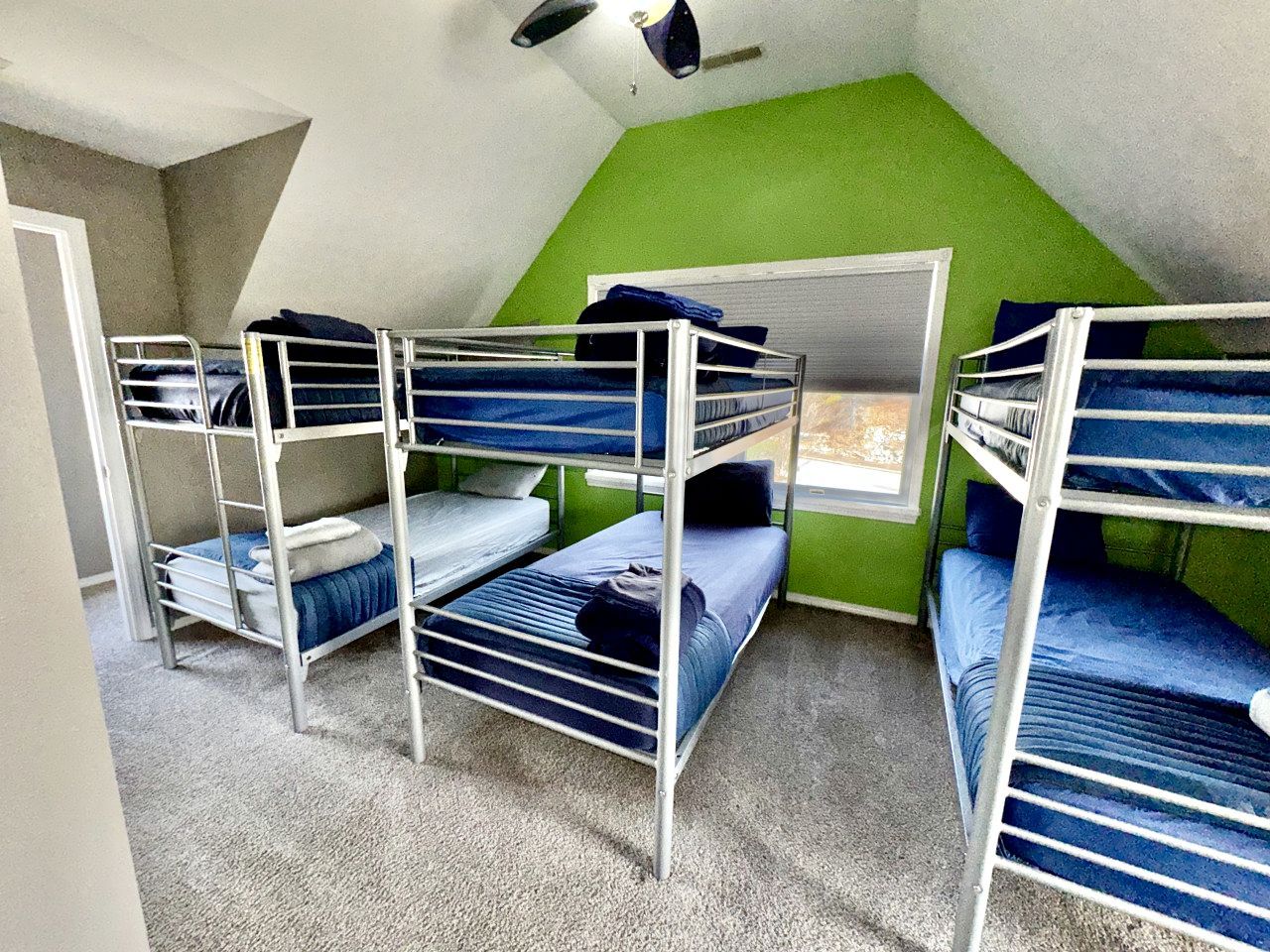 Une chambre de dortoir avec des lits superposés, un mur d’accent de couleur verte et une fenêtre.