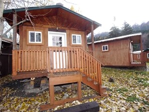 A wooden cabin with a porch, a door, and windows.
