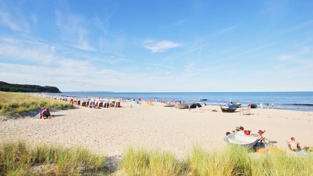 Ein Strand mit Reihen von Sonnenschirmen und Booten, der einen Strandort andeutet.