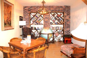 Ein Zimmer mit Backsteinwand, Globus, Bücherregalen, einem Esstisch mit Stühlen und einer Lampe.