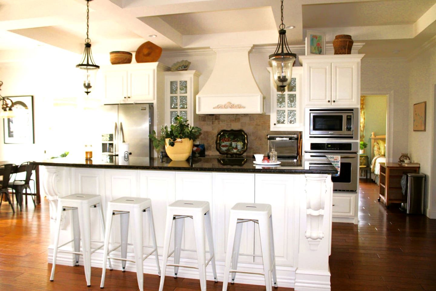 A kitchen with white cabinetry, a central island with bar stools, and various appliances.
