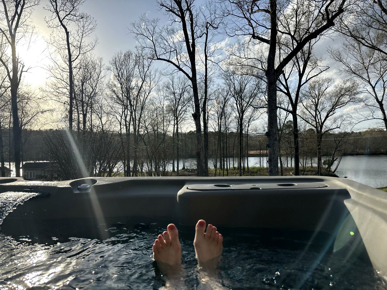 A hot tub with a view of trees and a body of water.