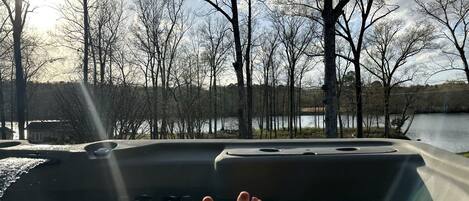 A hot tub with a view of trees and a body of water.