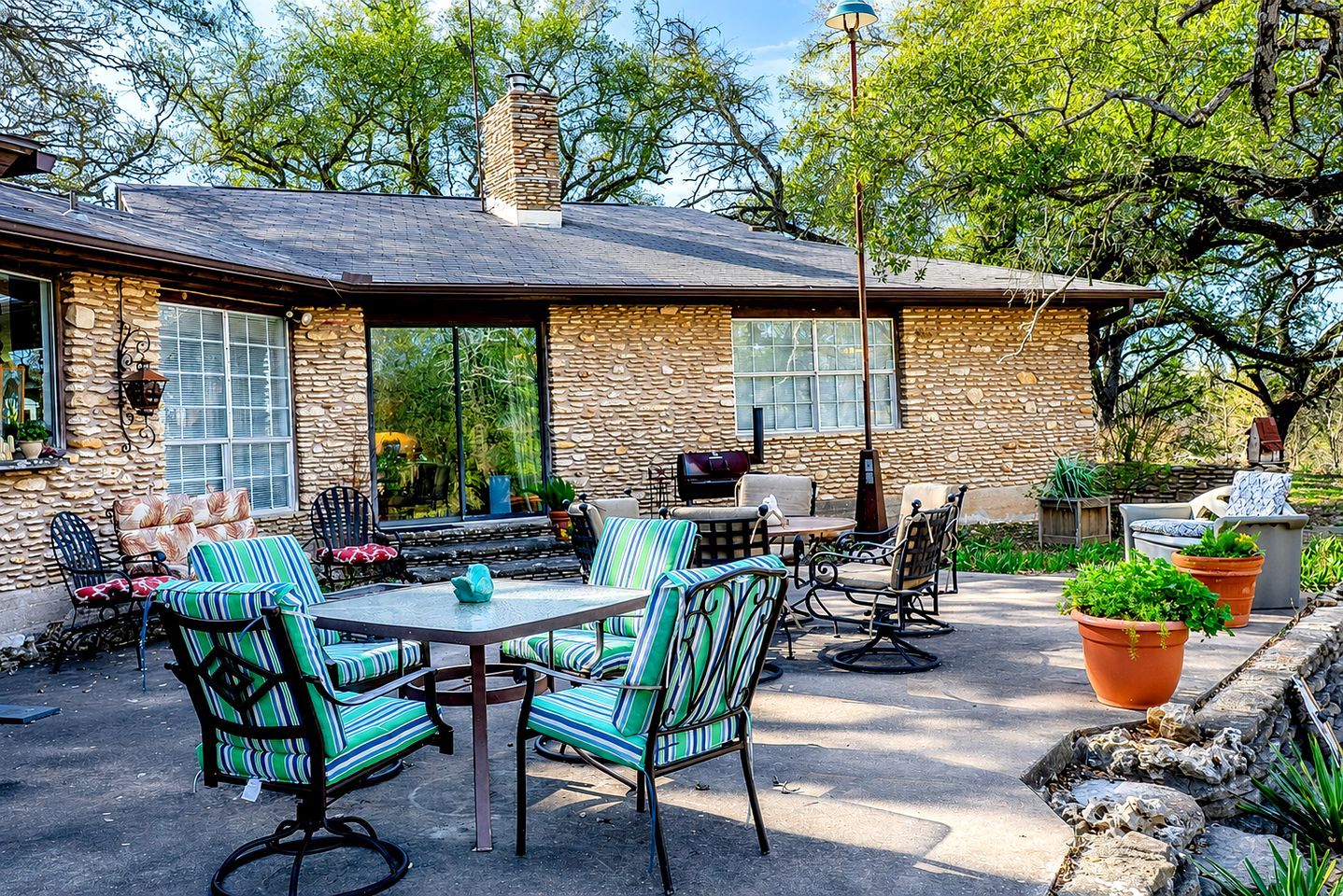 A stone house with a patio, outdoor seating, and potted plants.