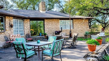 A stone house with a patio, outdoor seating, and potted plants.
