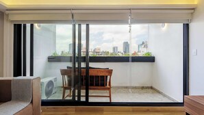 Uma sala de estar moderna com uma porta de vidro deslizante que dá para uma varanda com vista para a cidade.