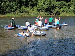 Personas en balsas inflables en un río rodeado de vegetación.