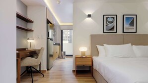 Hotelkamer met een bed, nachtkastjes, een bureau met stoel, een koelkast en een raam.