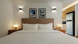 Een hotelkamer met een groot bed, twee nachtkastjes met lampen, een hoofdbord en twee ingelijste foto's aan de muur.