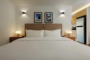 A hotel room with a large bed, two bedside tables with lamps, a headboard, and two framed pictures on the wall. - w* | Serene Loft w/ Elegant Balcony in Colima (Ciudad de México)