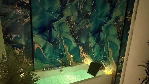 Ein Wellnessbereich mit Marmorwand, Badewanne und kleinem Pool.
