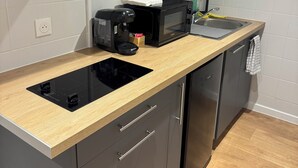 Eine moderne Küche mit einem schwarzen Induktionskochfeld, einer eingebauten Mikrowelle und einem Edelstahl-Geschirrspüler.