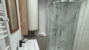 Ein modernes Badezimmer mit Duschkabine aus Glas, einem weißen Waschbecken und einer Toilette.