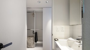 Un baño moderno con una bañera blanca, zona de ducha y un armario empotrado.
