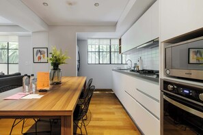 Eine moderne Küche mit weißen Schränken, einem Holzespeisetisch und einem eingebauten Backofen.