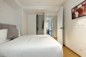 Ein modernes Hotelzimmer mit einem großen Bett, einem Kleiderschrank und einem Flur zu weiteren Räumen.
