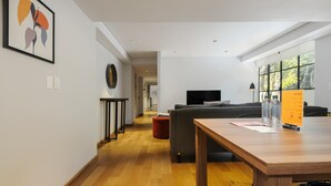 Una sala de estar moderna con una mesa de comedor de madera, un sofá y un televisor.