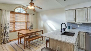 Una cocina con una mesa de madera, un banco y un ventilador de techo.