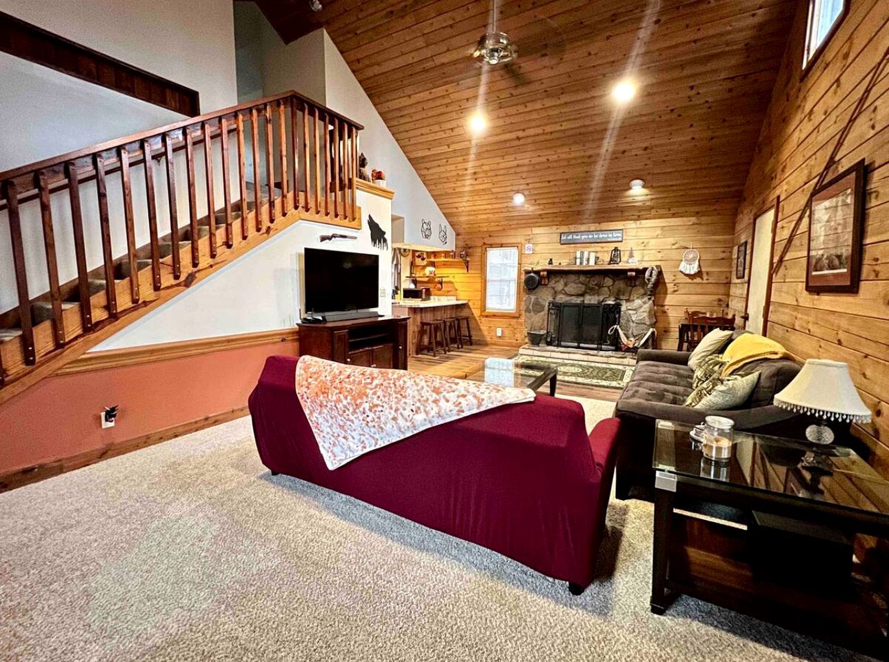Uma sala de estar aconchegante com um sofá vermelho, escada de madeira e lareira.