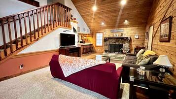 Uma sala de estar aconchegante com um sofá vermelho, escada de madeira e lareira.