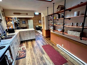 Une cuisine dotée d’un îlot central, d’un plancher en bois et d’un tapis rouge.
