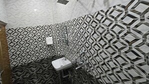 A bathroom with patterned tiles, a sink, and a shower head. - Rudra PGH - just near Temple & Ghats (Varanasi)