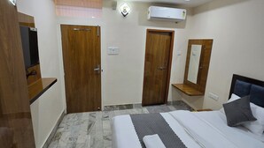 A hotel room with a bed, a ceiling fan, an air conditioning unit, and a wooden door. - Rudra PGH - just near Temple & Ghats (Varanasi)