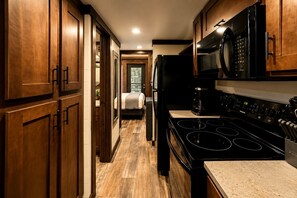 A kitchen with wooden cabinets, a stove, and a microwave. - Gorgeous Cabin with Hot-tub and Games in Monteagle, Tennessee (Monteagle)