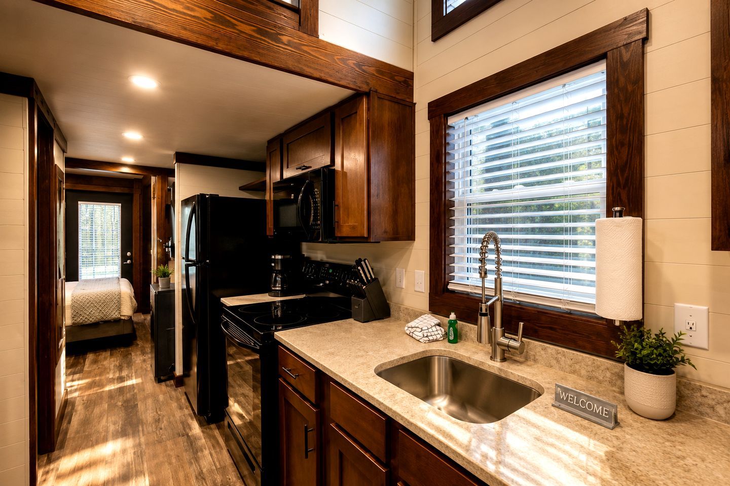 Cocina compacta con armarios de madera, refrigerador negro, estufa y pileta.