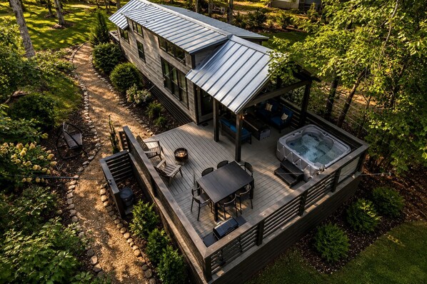 Una casa moderna de dos pisos con terraza, mobiliario exterior y un jacuzzi.