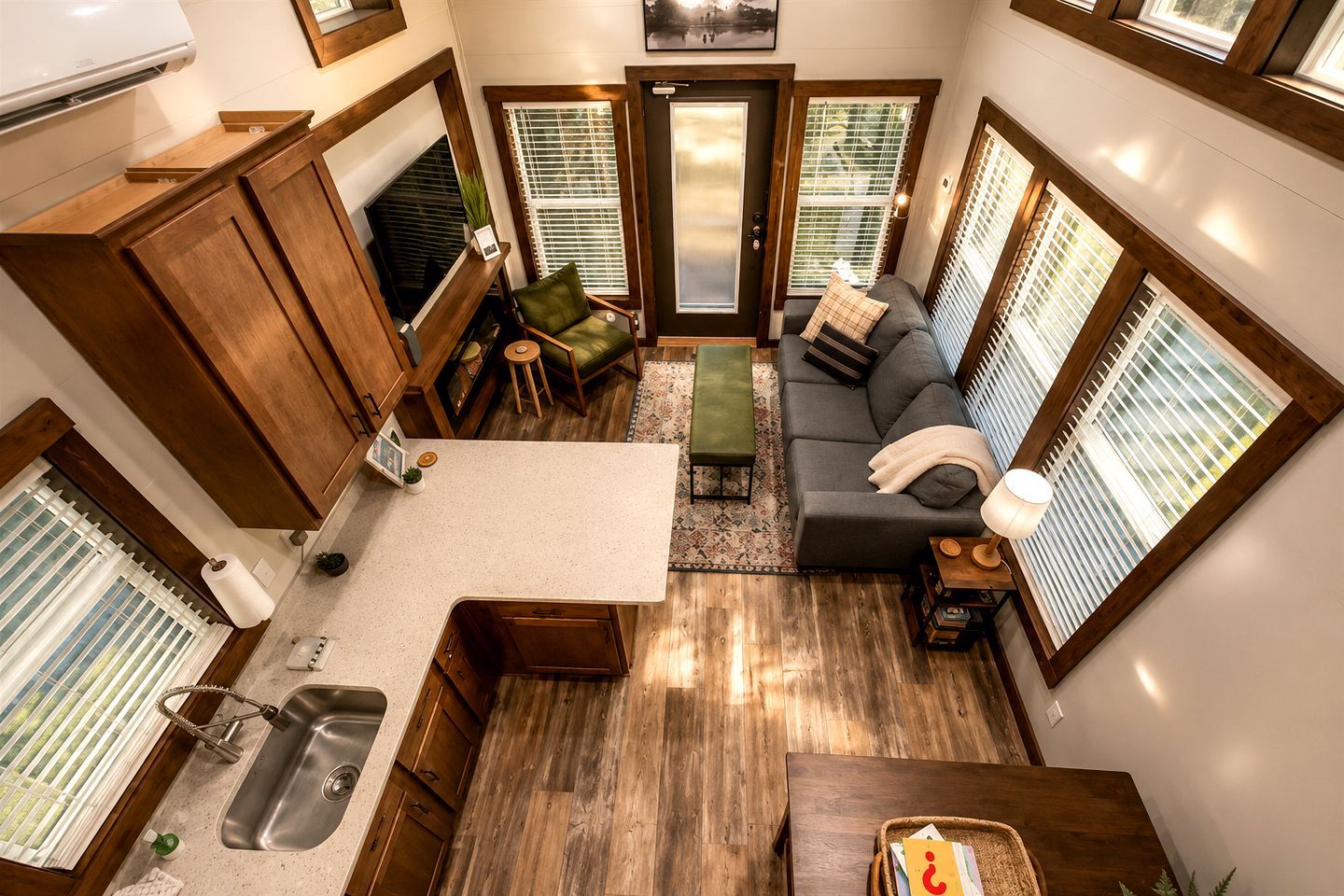 Un espacio habitable pequeño con kitchenette, zona de estar y ventanas amplias.