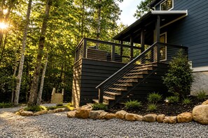 A modern house with a wooden staircase leading to a covered porch.