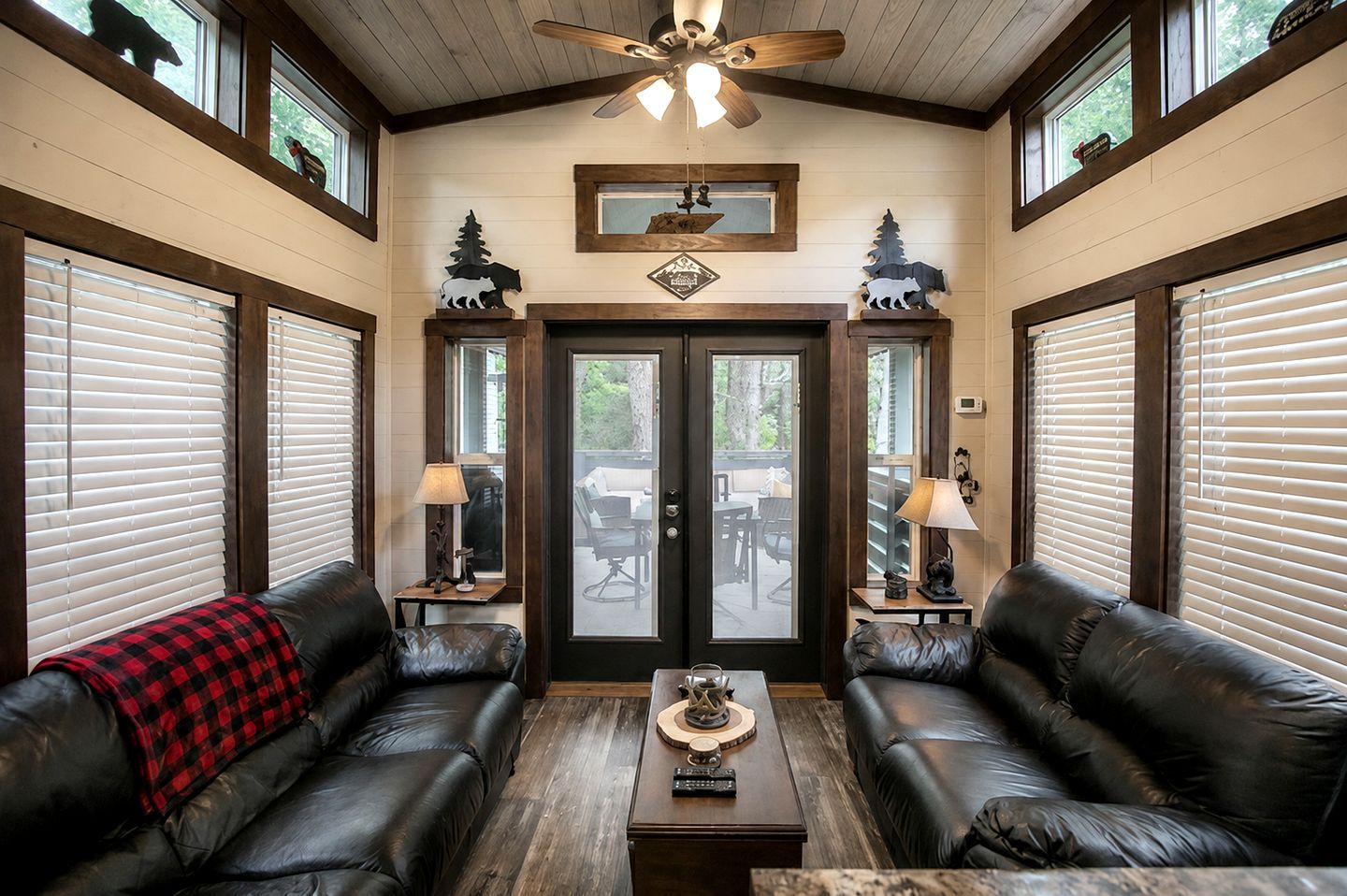 A room with two leather sofas, a wooden coffee table, and a ceiling fan.