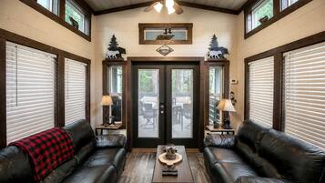 A room with two leather sofas, a wooden coffee table, and a ceiling fan.