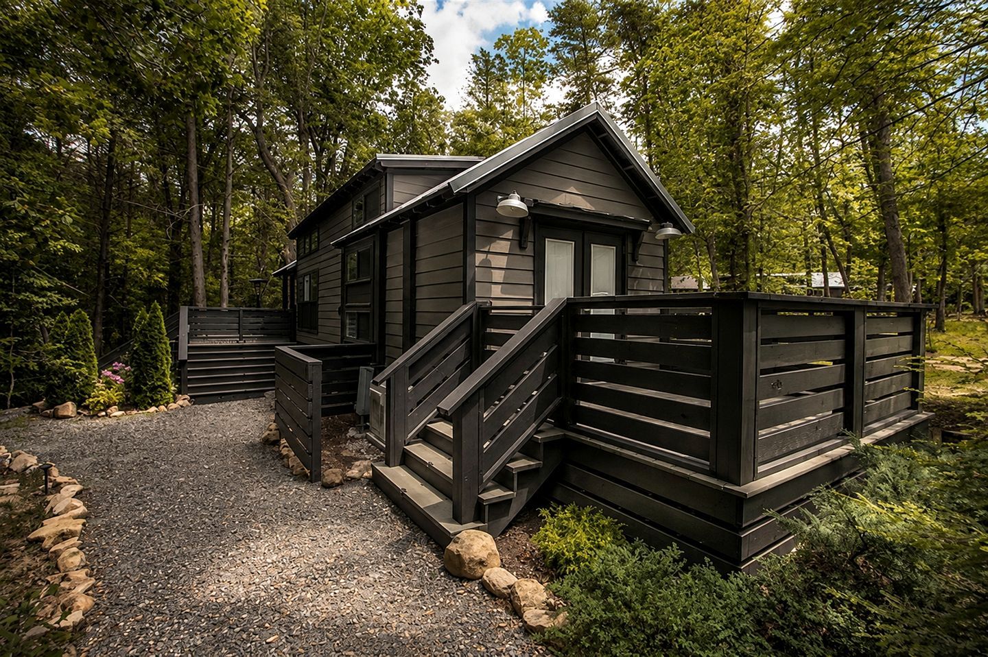 A cabin with a gravel driveway and a wooden fence.