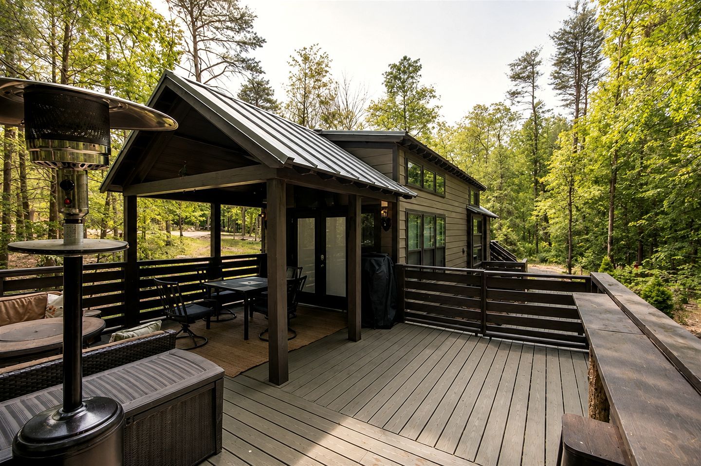 A wooden deck with outdoor seating, a covered area, and a building with large windows.