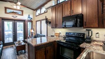 A kitchen with wooden cabinets, a granite countertop, a stove, and a sink.