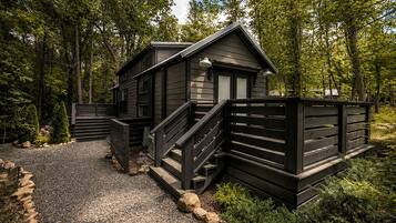 A cabin with a gravel driveway and a wooden fence.