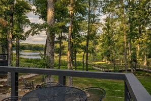 A deck with outdoor seating overlooking a lake and forest. - Tranquil Cabin with Fire Pit and Panoramic Lake Views in Tennessee (Tracy City)