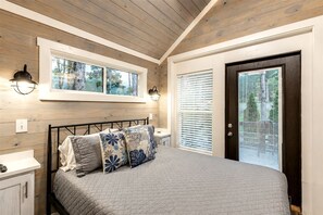 A bedroom with a bed, a window, a door, and a wall-mounted light fixture. - Tranquil Cabin with Fire Pit and Panoramic Lake Views in Tennessee (Tracy City)
