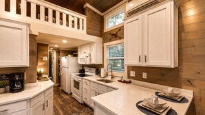 A modern kitchen with white cabinetry, a central island, and a wooden ceiling. - Tranquil Cabin with Fire Pit and Panoramic Lake Views in Tennessee (Tracy City)