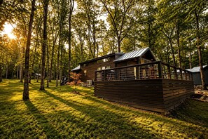 Eine Hütte mit einer Terrasse, umgeben von Bäumen und Gras.